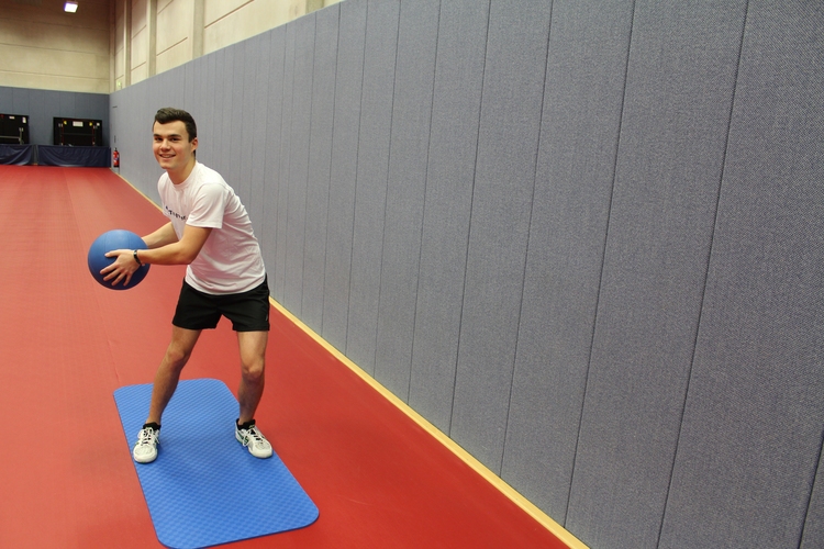 Übung 3 (Medizinballwurf gegen Wand "seitlich"): Gehen Sie leicht in die Knie und drehen den Rumpf beim Ballwurf. (©Schäbitz)